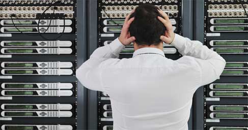 Person in front of server rack holding hands to head